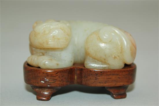 A Chinese pale celadon and russet jade recumbent figure of a bixi, 19th century, 5cm, wood stand